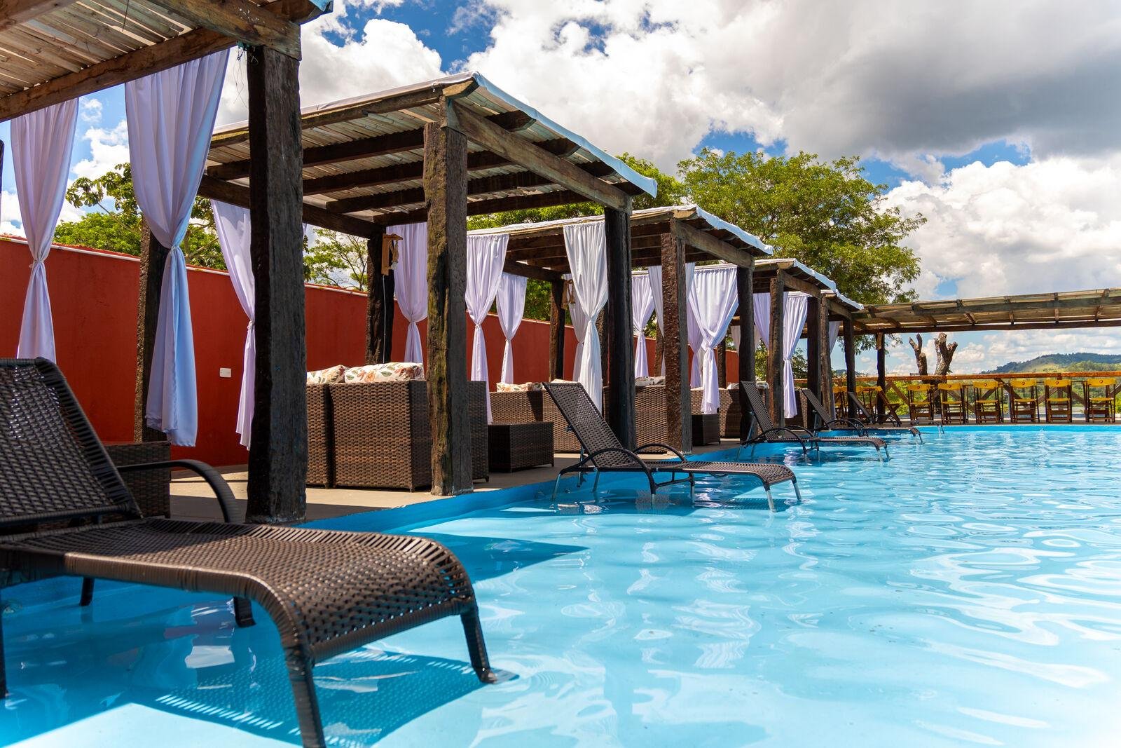Espreguiçadeiras dentro da piscina com os bangalôs ao fundo
